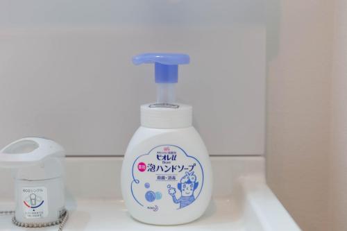 a bottle of liquid soap sitting on a bathroom sink at Guest House MEGU-chan in Osaka