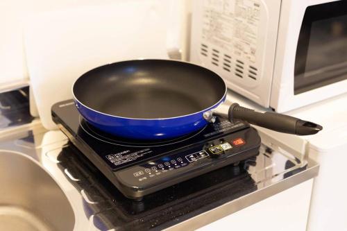 a frying pan sitting on top of a microwave at Guest House MEGU-chan in Osaka