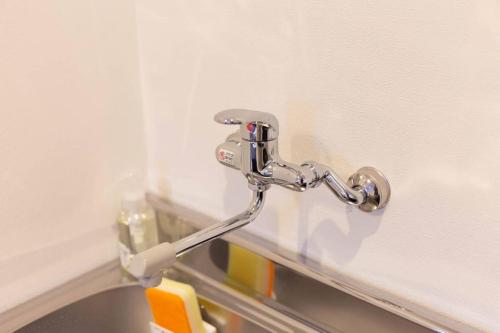 fermeture d'un robinet métallique sur une paroi dans l'établissement Guest House MEGU-chan, à Osaka