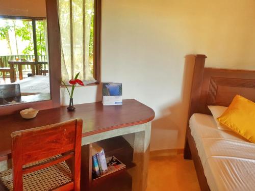 a bedroom with a desk and a bed and a window at Guruwaththa Eco Lodge in Hikkaduwa
