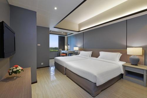 een slaapkamer met een groot bed en een televisie bij Tinidee Hotel Bangkok Golf Club - SHA Certified in Pathum Thani