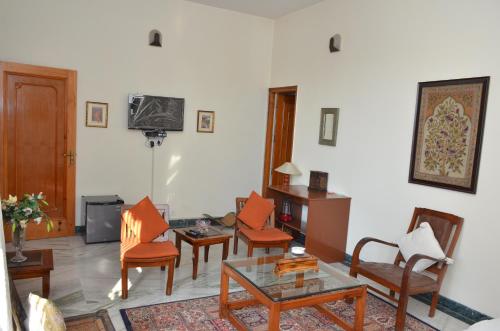 a living room with chairs and a table and a tv at Sandy's Homestay in Jammu