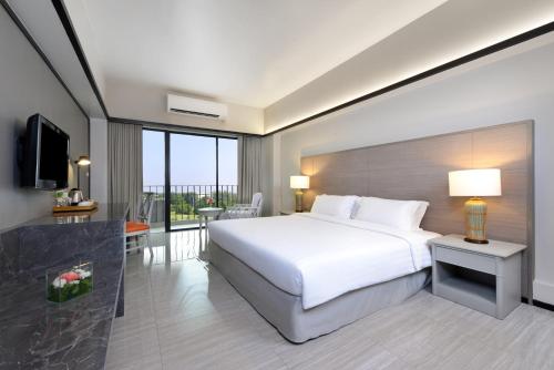 a bedroom with a large white bed and a balcony at Tinidee Hotel Bangkok Golf Club in Pathum Thani