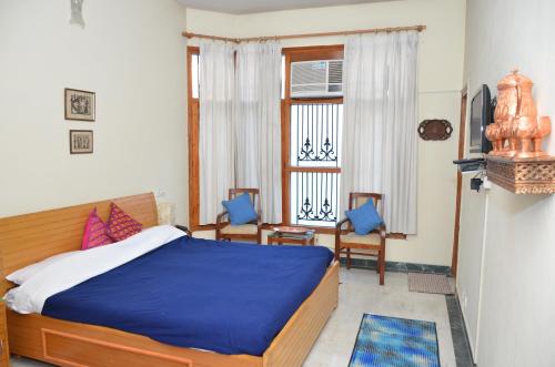 een slaapkamer met een bed en 2 stoelen en een raam bij Sandy's Homestay in Jammu