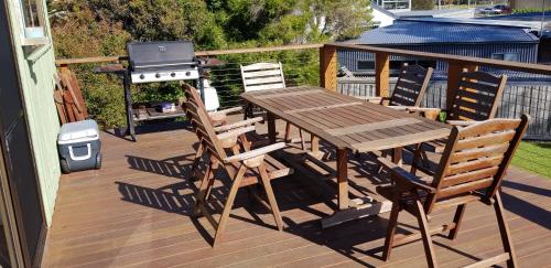 a wooden table and chairs on a deck with a grill at 4 Bounty in Corinella