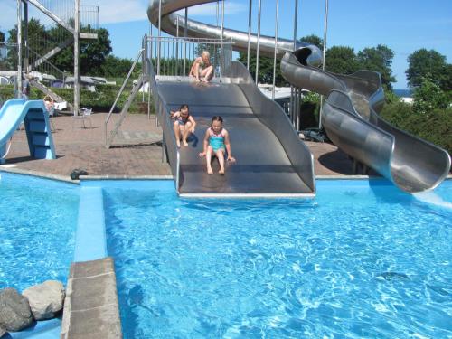 three children playing on a slide in a swimming pool at Dancamps Trelde Naes (Camp Site) in Fredericia