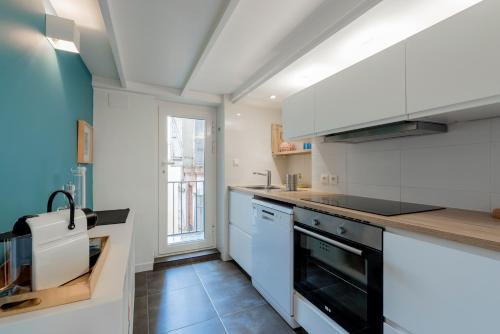 une cuisine avec des armoires blanches et un four noir dans l'établissement Le Cocon de la Daurade by Cocoonr, à Toulouse