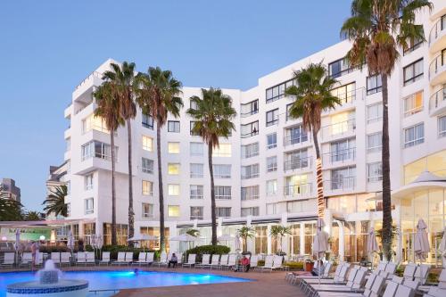 a large white building with palm trees and a pool at President Hotel in Cape Town