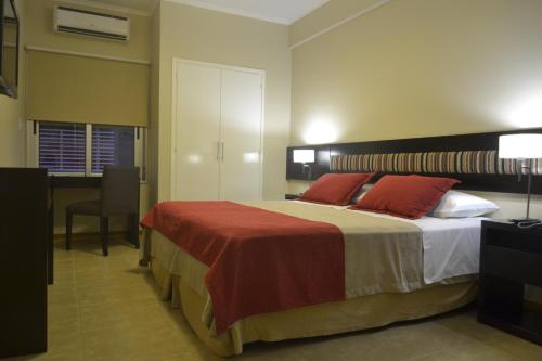 1 dormitorio con cama con almohadas rojas y escritorio en Almuñecar Hotel en Tartagal