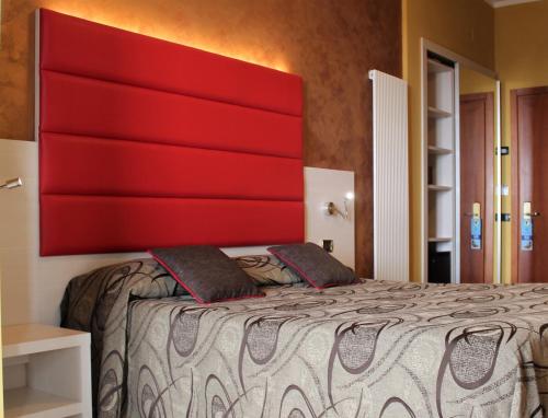 a bed with a red headboard in a room at Hotel Eco Del Mare in Marina di Massa