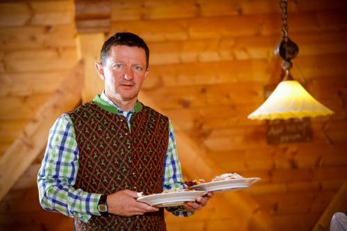 a man is holding a plate of food at Hotel Edelweiss in Hochfilzen