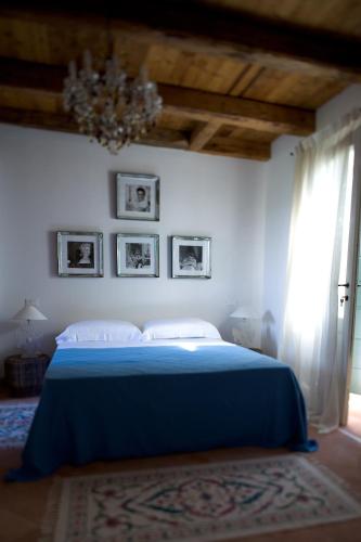 a bedroom with a blue bed and a chandelier at Borgo Dei Conti Della Torre in Morsano al Tagliano