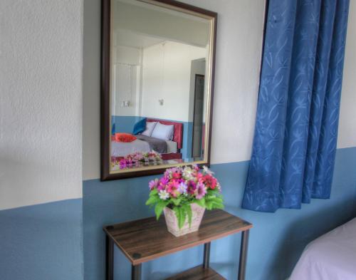 a mirror on a wall next to a table with flowers at Sams ChiangKhan in Chiang Khan