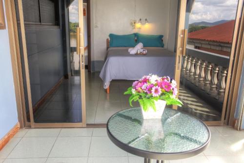 a bedroom with a bed and a table with a vase of flowers at Sams ChiangKhan in Chiang Khan