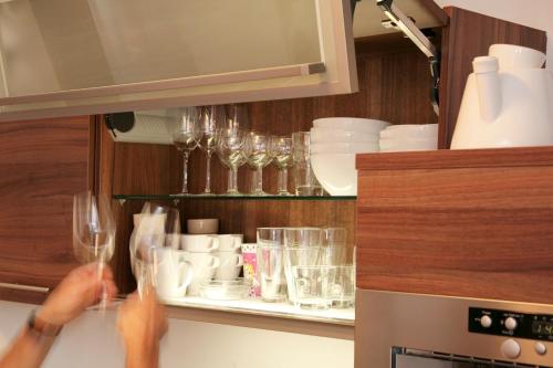a person holding up wine glasses in a kitchen at EXCLUSIVE APARTMENTS - inclusive Zell am See-Kaprun Sommerkarte und unbegrenztem Tauern SPA Eintritt in Kaprun