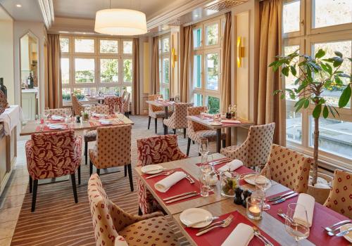 a restaurant with tables and chairs and windows at Landhotel Kallbach - 4 Sterne SUPERIOR in Hürtgenwald