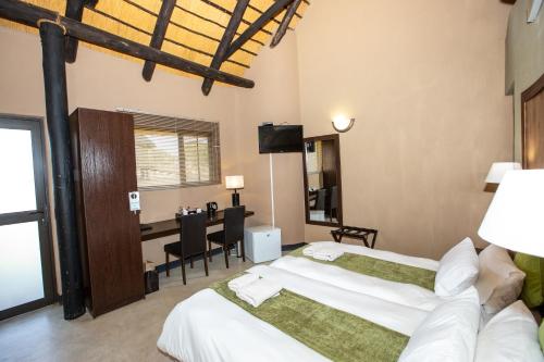 a hotel room with two beds and a desk at Lapa Lange Game Lodge in Mariental