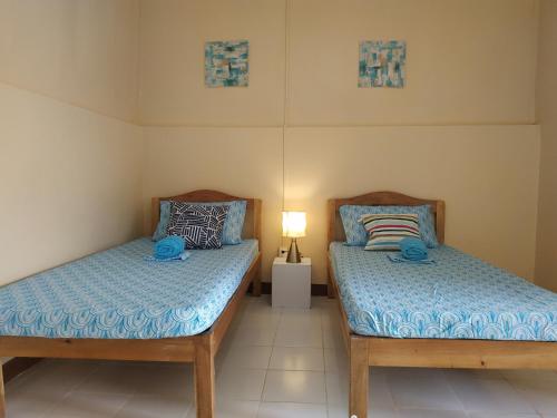 two twin beds in a room with a lamp at Nelmann's Nipa Huts in San Vicente