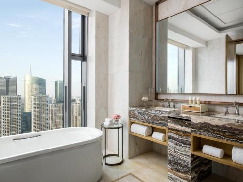 a bathroom with a tub and a large window at The Langham, Hefei in Hefei