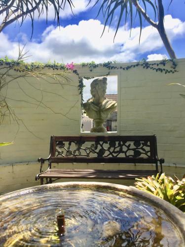 a statue sitting on a bench in a garden at St. Lucia Wetlands Guest House in St Lucia