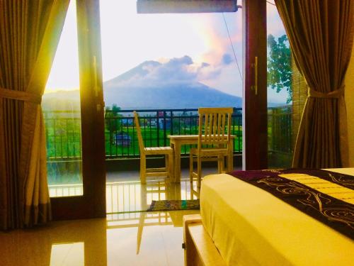 a bedroom with a balcony with a view of a mountain at D'uma Amed Homestay in Amed