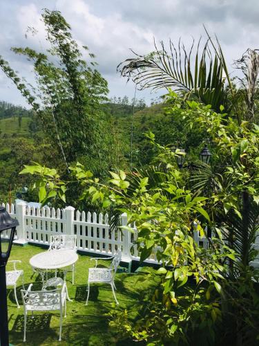 a table and chairs in a yard with a white fence at Hotel Mount Castle in Hatton