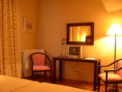 a room with a bed, desk, chair and lamp at Hotel Rural El Jardin de la Hilaria in Valsain