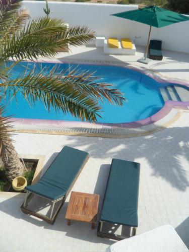two lounge chairs and an umbrella next to a swimming pool at Maison Leila chambres d hotes in Midoun