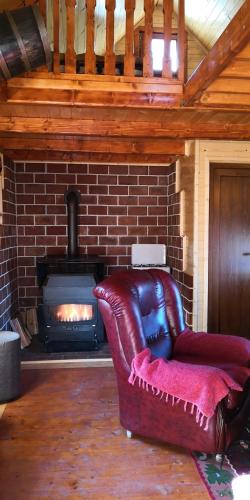 a leather chair in front of a brick fireplace at Koliba Pčelica 1-SPA in Bijelo Polje