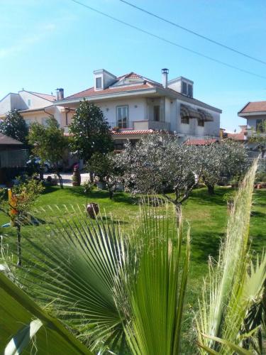 a house with a green yard with trees in front of it at Le Magnolie B&B in Roseto degli Abruzzi