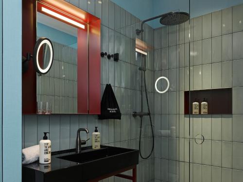 a bathroom with a sink and a shower with a mirror at 25hours Hotel The Trip in Frankfurt/Main