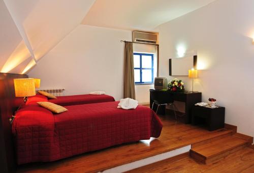 a bedroom with a red bed and a desk at INATEL Piodao in Piódão