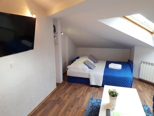 um pequeno quarto com uma cama e uma televisão em Apartament City Center Studio DeLuxe em Krynica-Zdrój