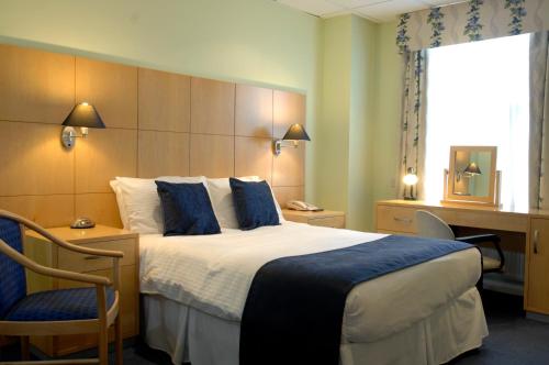 a hotel room with a large bed and a desk at Lysses House Hotel in Fareham
