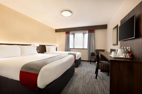 a hotel room with two beds and a desk at Ramada Bristol West in Easton in Gordano