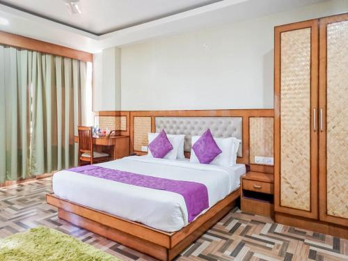 um quarto com uma cama grande e almofadas roxas em Pemaling Lords Eco Inn Guwahati em Guwahati