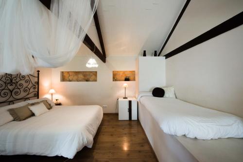ベルモンテにあるEl Loft de La Cocheraの白い壁とウッドフロアの客室で、ベッド2台が備わります。