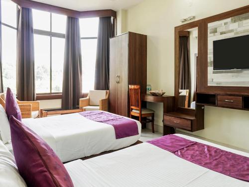 a hotel room with two beds and a flat screen tv at Pemaling Lords Eco Inn Guwahati in Guwahati