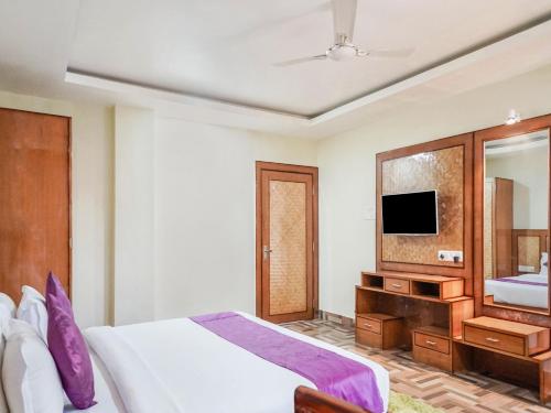 a bedroom with a bed and a mirror and a tv at Pemaling Lords Eco Inn Guwahati in Guwahati