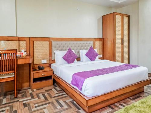 a bedroom with a large bed with purple pillows at Pemaling Lords Eco Inn Guwahati in Guwahati