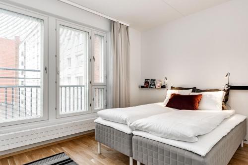 a bedroom with a bed with white sheets and windows at Haave Apartments Tampere in Tampere