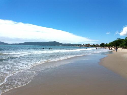 una playa con un montón de gente caminando en el agua en Canasvieiras - Residencial Costa do Mar, en Florianópolis