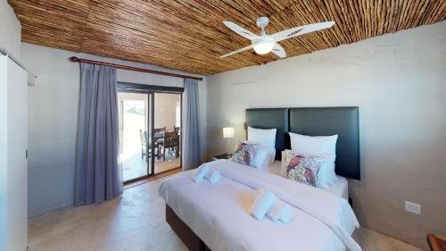 a bedroom with two beds and a ceiling fan at Swartberg Pass Cottages in Matjiesrivier
