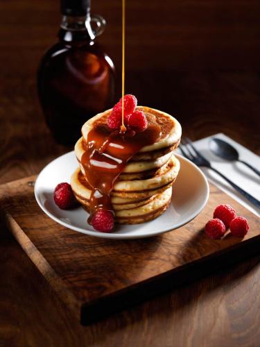 a plate of pancakes with strawberries and syrup on a table at Road House Hotel in Paderborn
