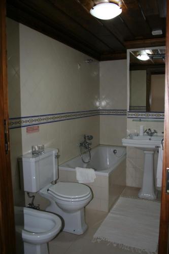 a bathroom with a toilet and a sink and a tub at Casa De Carcavelos in Cabeceiras de Basto