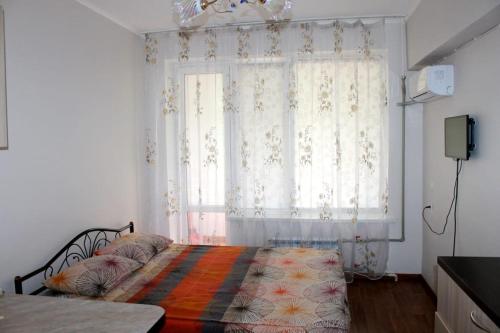 a bedroom with a bed and a window with curtains at Apartments Zhambyl 159 in Almaty