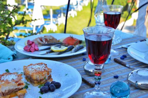 a table with plates of food and two glasses of wine at Belussi Beach Hotel & Suites in Kipseli