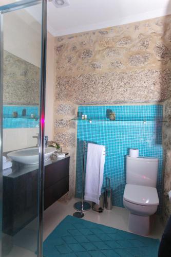 a bathroom with a toilet and a sink and blue tiles at Casa De Carcavelos in Cabeceiras de Basto