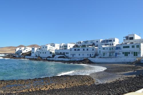 un grupo de edificios blancos en una playa en Casa Cabrera - 2 apartamentos con vistas al mar en Caleta de Caballo