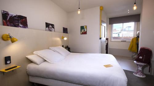 a bedroom with a large white bed and a window at ARTYSTER CLERMONT-FERRAND in Clermont-Ferrand